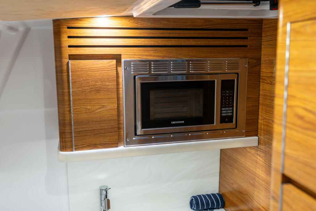 Cabin galley microwave oven built into rich wood cabinetry with stainless steel trim