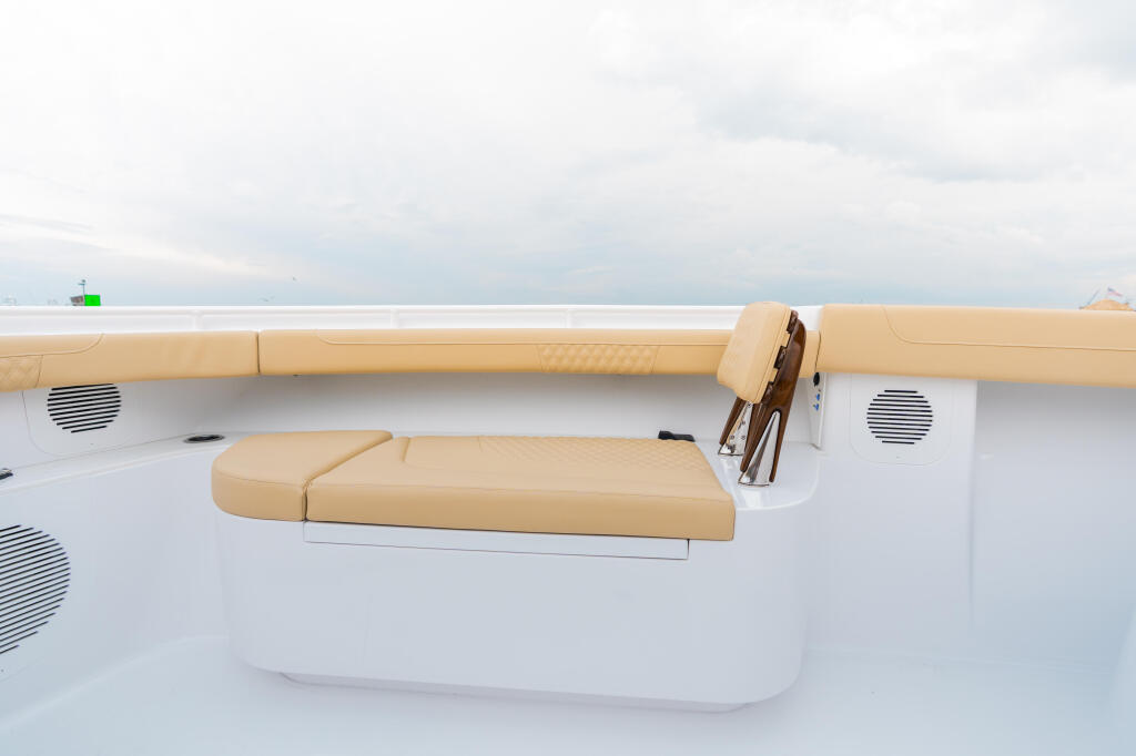 Tan cushioned seating with storage along the boat's gunwale overlooking calm water