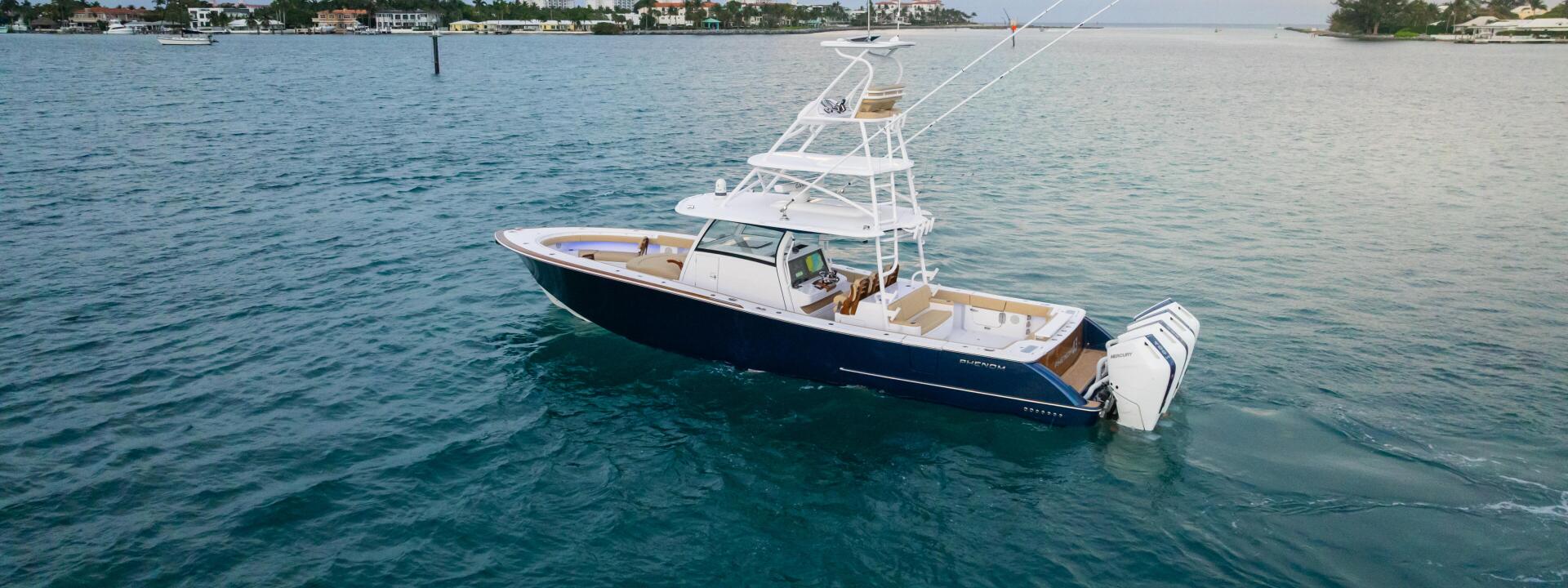Sport fishing boat anchored in calm turquoise water with residential shoreline in the background