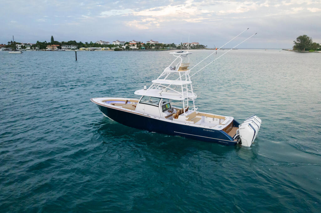 Sport fishing boat anchored in calm turquoise water with residential shoreline in the background