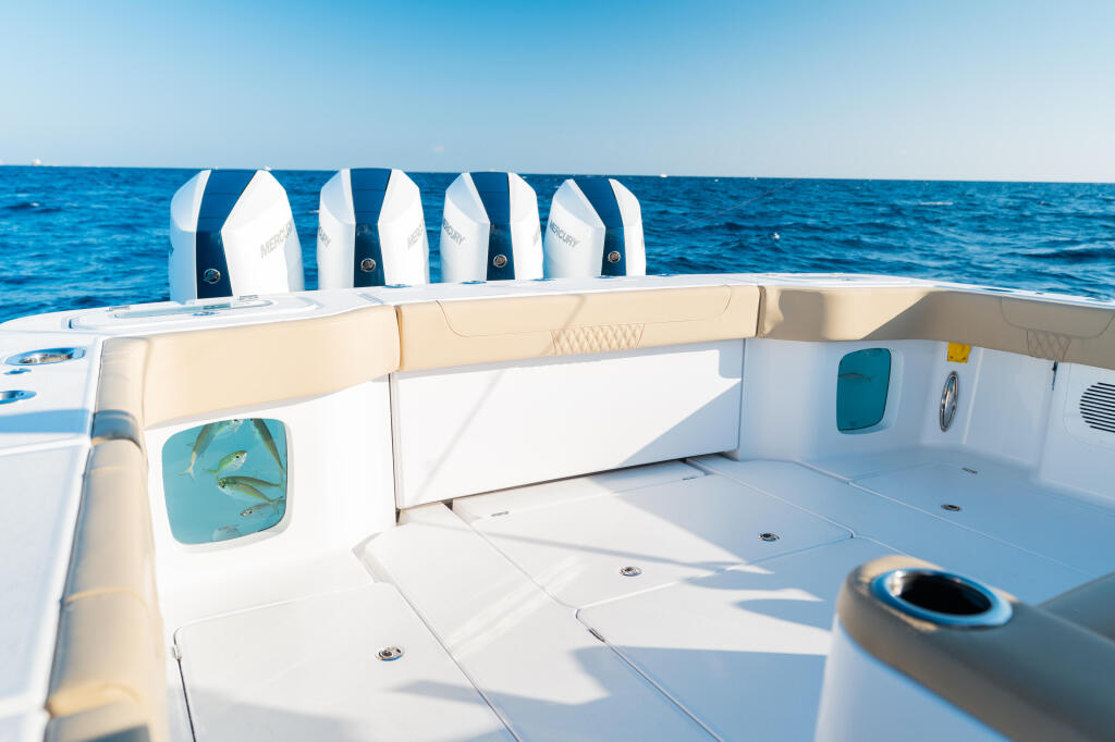 Spacious cockpit with cream-colored flip-down bench seating and life jackets stored along the transom, overlooking blue open water