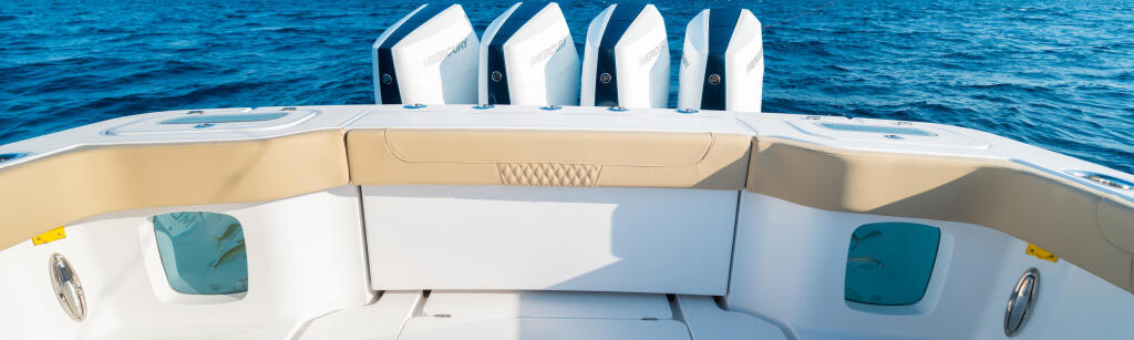 Four white outboard engines mounted on transom above a spacious white boat cockpit with tan seating and tinted windows