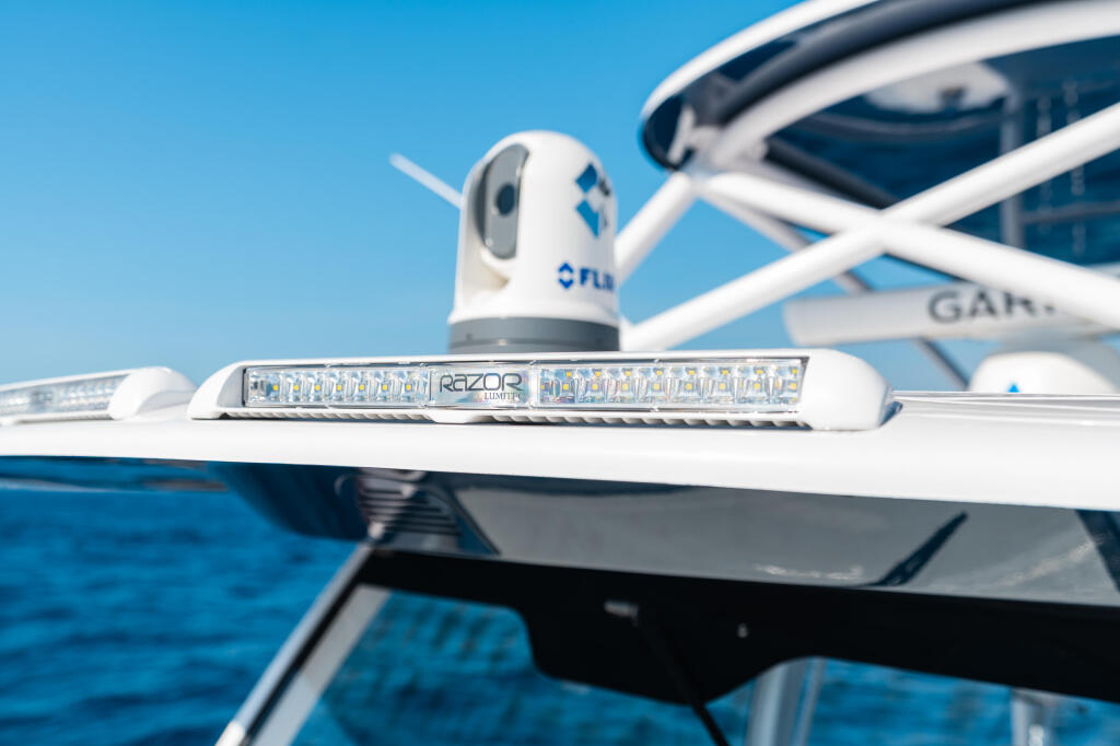 Razor spreader light and 360-degree rotating spotlight mounted on boat hard-top above open water