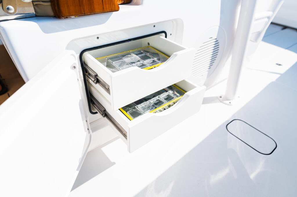 Open tackle storage drawers with yellow-handled fishing tackle boxes mounted on boat console