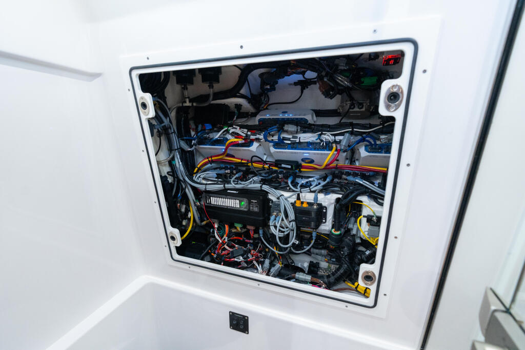 Boat engine compartment showing marine electronics, wiring harness, battery systems, and JL Audio amplifiers installed