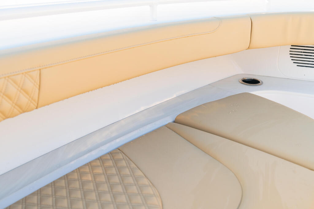 Cream and white upholstered seating with quilted cushions and storage compartment in boat cabin