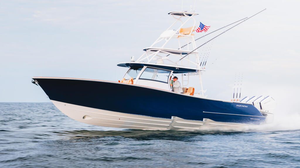 Navy and white sport fishing yacht with hard-top running at speed through offshore waters
