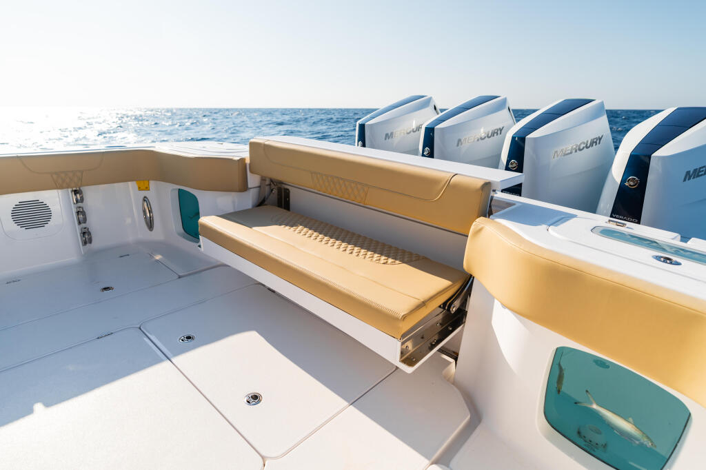 Stern seating area with tan cushions, Mercury outboard engines, and open ocean backdrop