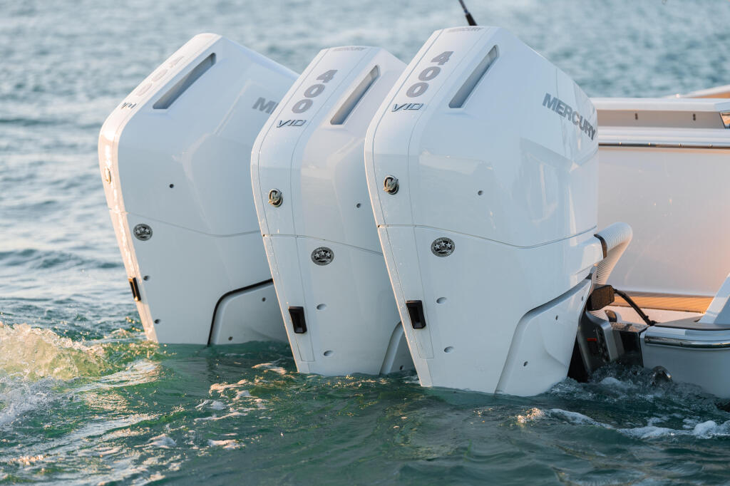 Three white Mercury Verado 400hp engines mounted on the transom of a boat at a beach