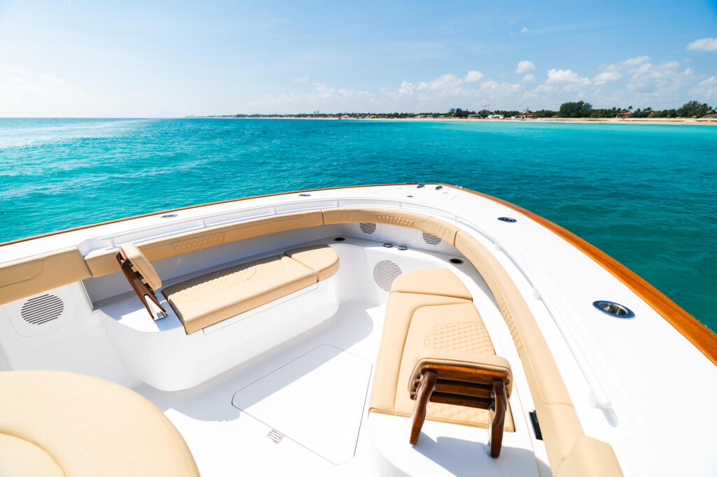 Spacious boat bow with cream-colored seating facing turquoise water and sandy beach