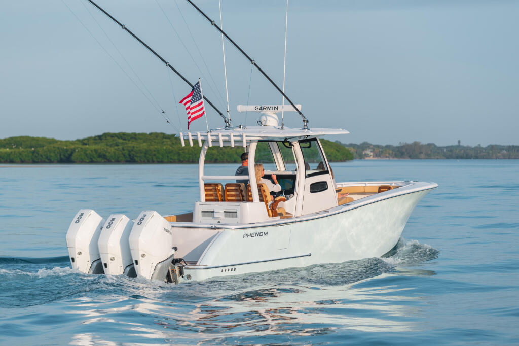 White sport fishing boat with triple Mercury Verado engines running in calm blue water, American flag flying, Garmin electronics visible on hardtop