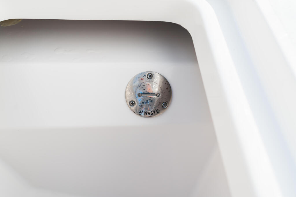 Close-up of a marine waste pump-out fitting mounted on white boat hull