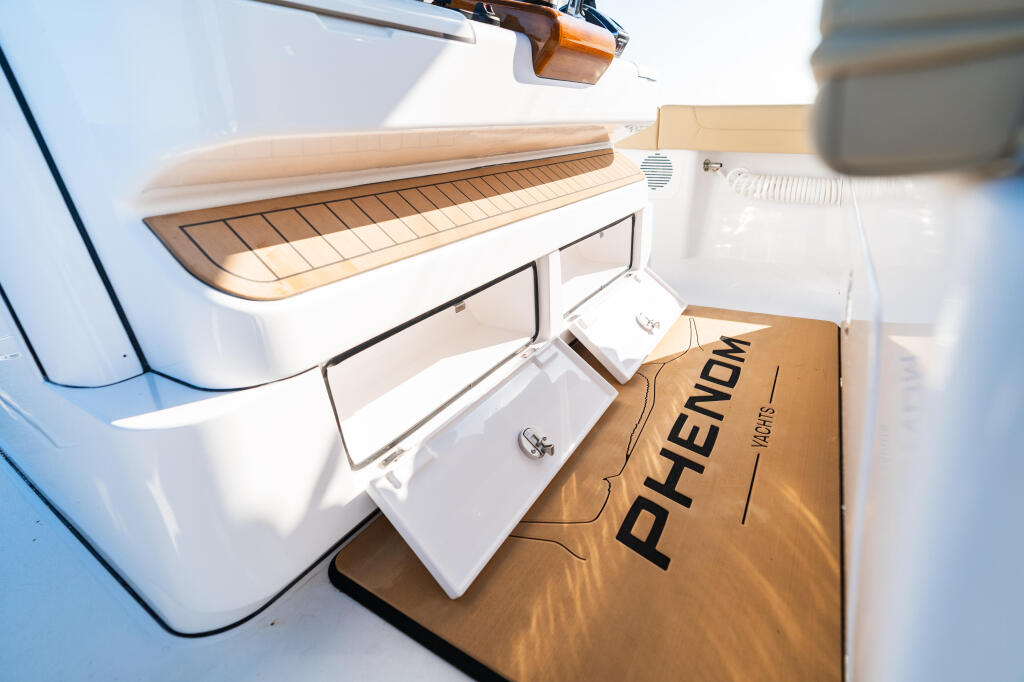Helm console detail showing storage compartments and teak wood accents on a Phenom boat