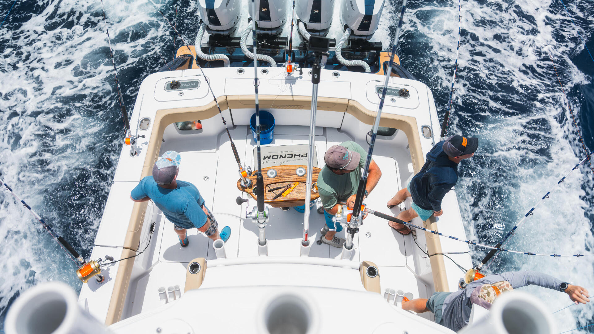 Aerial view of fishing boat with four anglers holding rods while cruising through offshore waters