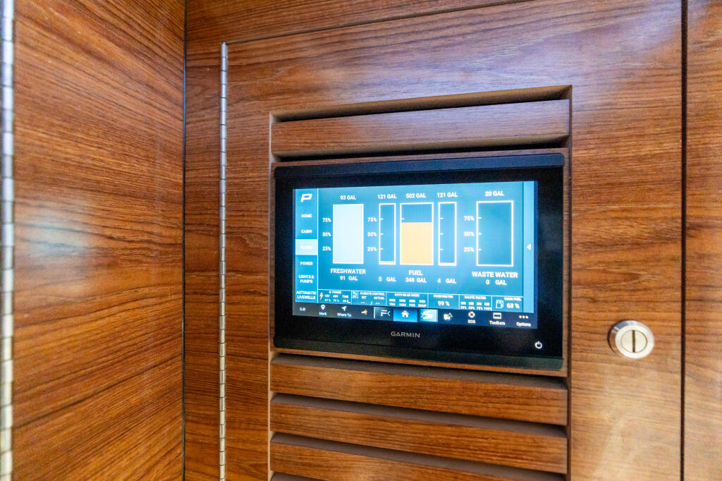 Garmin marine display showing tank levels and system status on wood-paneled cabin wall